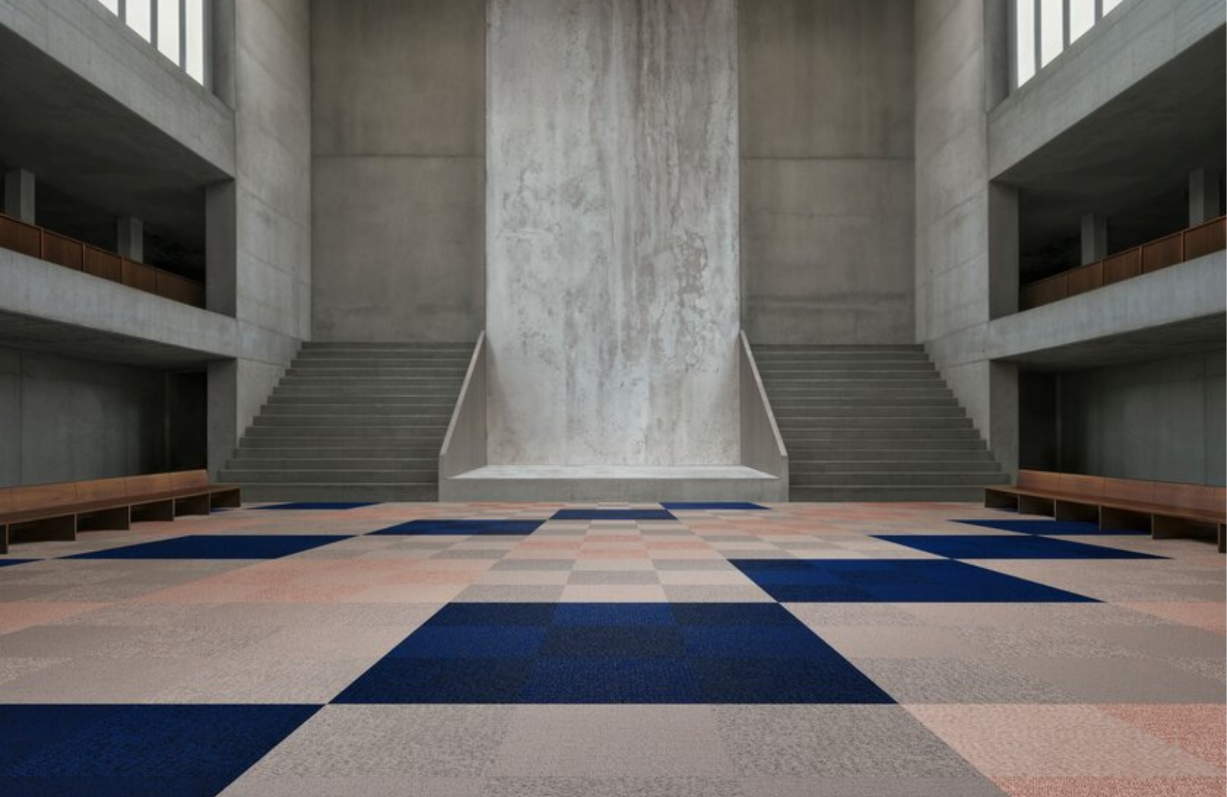 Spacious interior with concrete walls, wide stairs, and a geometric patterned floor in shades of blue, pink, and beige.