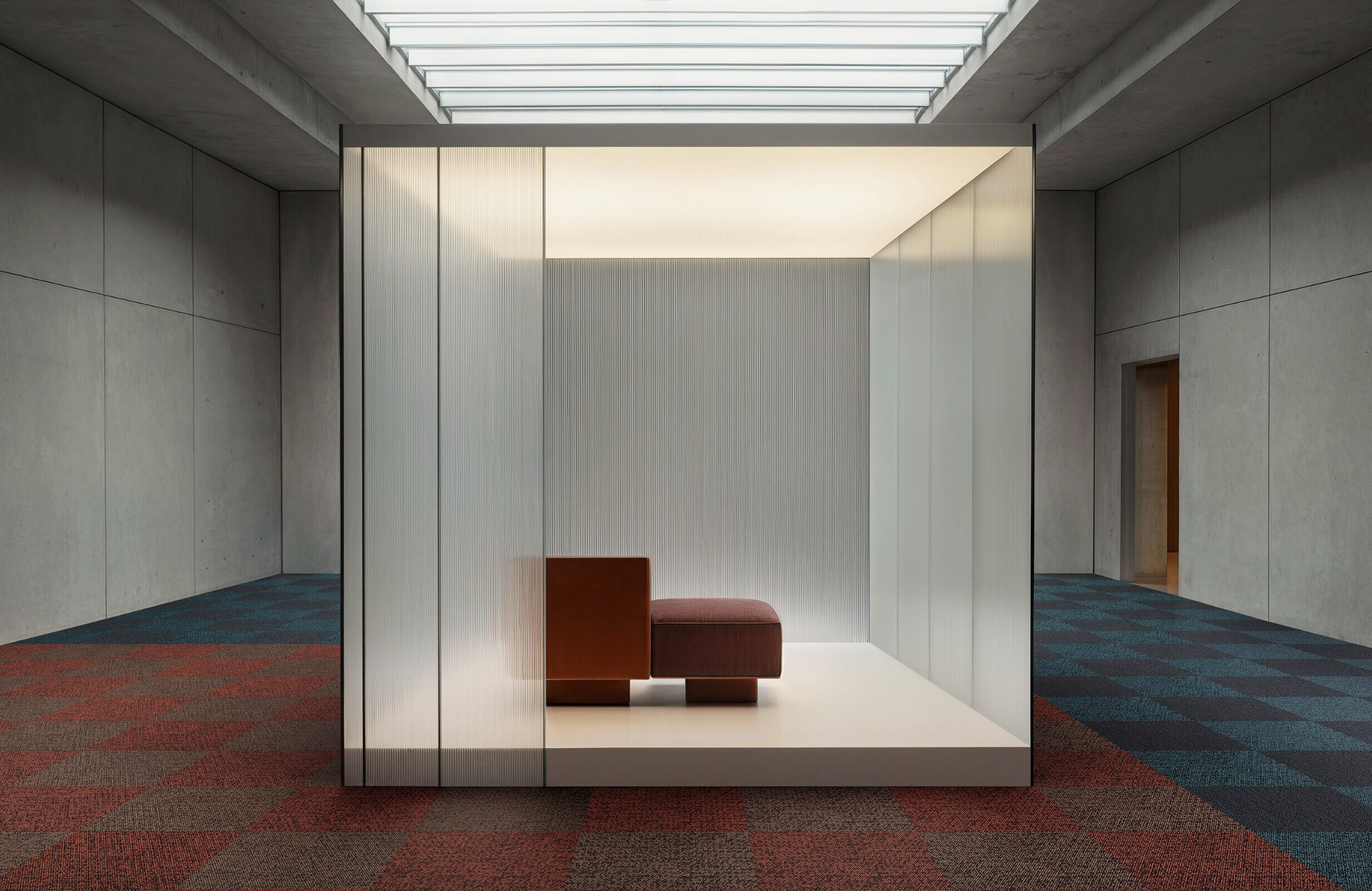 Contemporary architectural interior with geometric lighting, glass partitions, and textured Bolon flooring in red and blue tones, a study in minimalist design and material contrast.